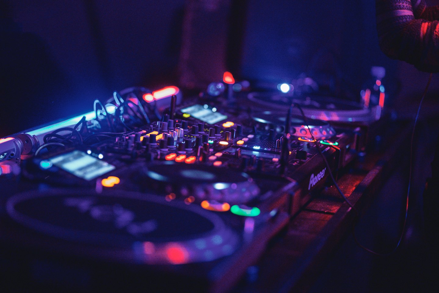 DJ-Mischpult und Plattenspieler mit leuchtenden Knöpfen im Club.