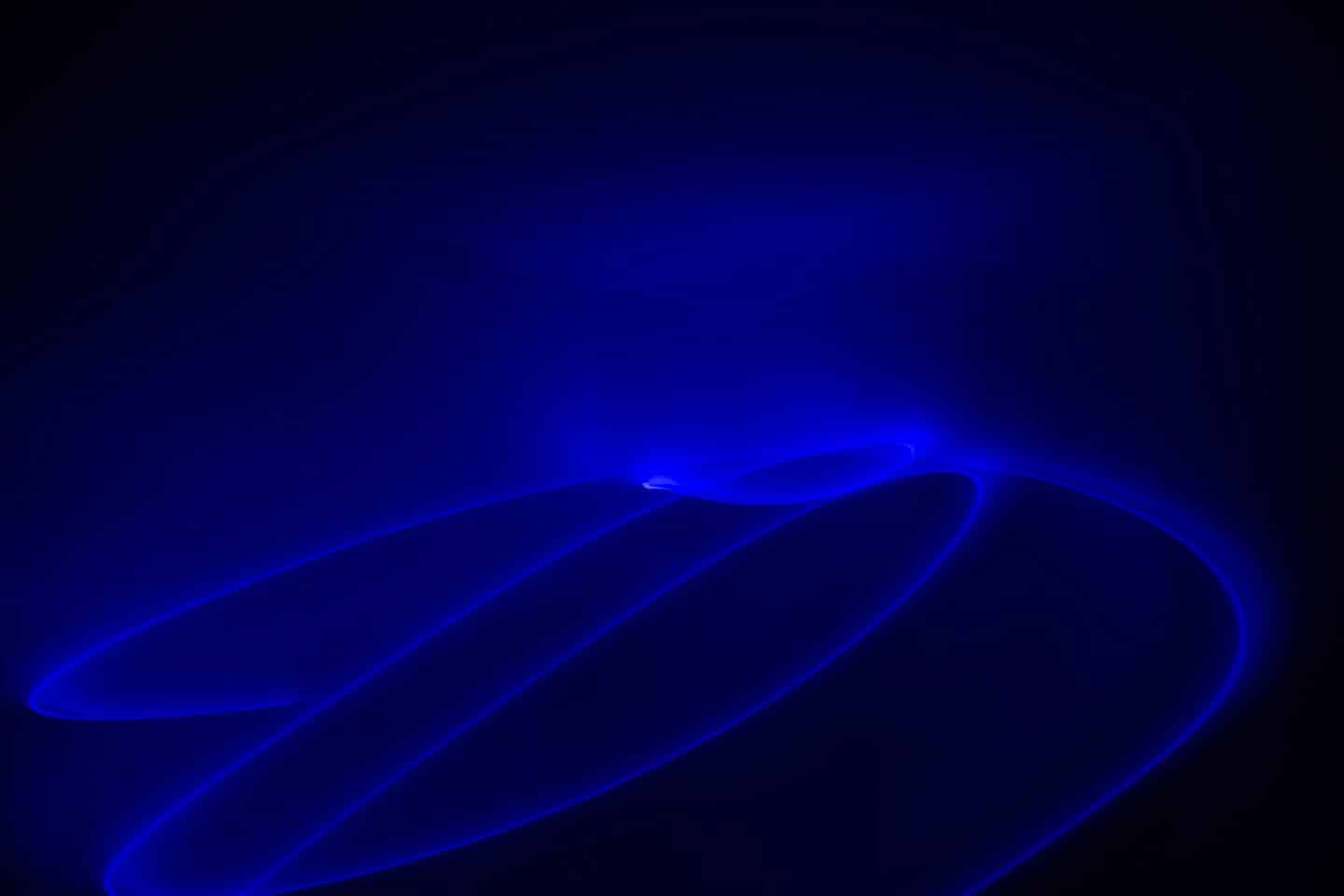 Leuchtende blaue Lichtspuren wirbeln vor einem dunklen Hintergrund nach oben.